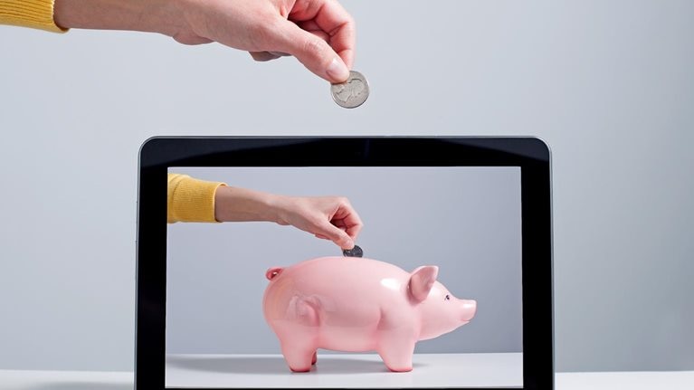 Person putting coin into digital piggy bank
