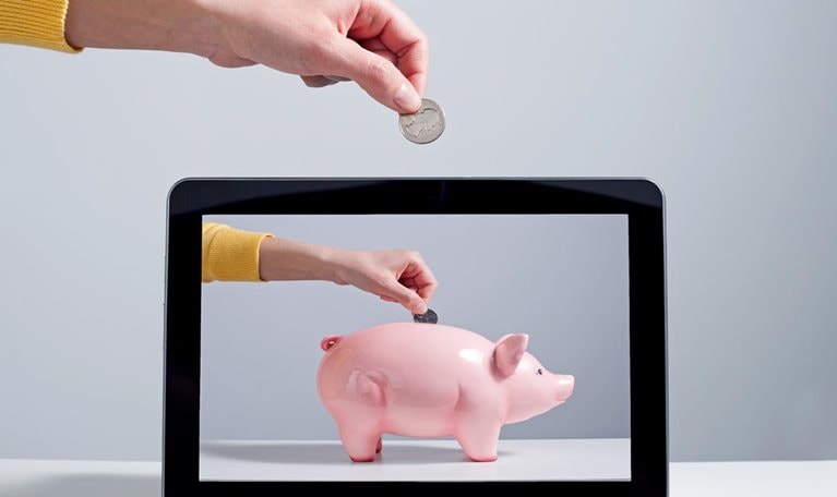 Person putting coin into digital piggy bank