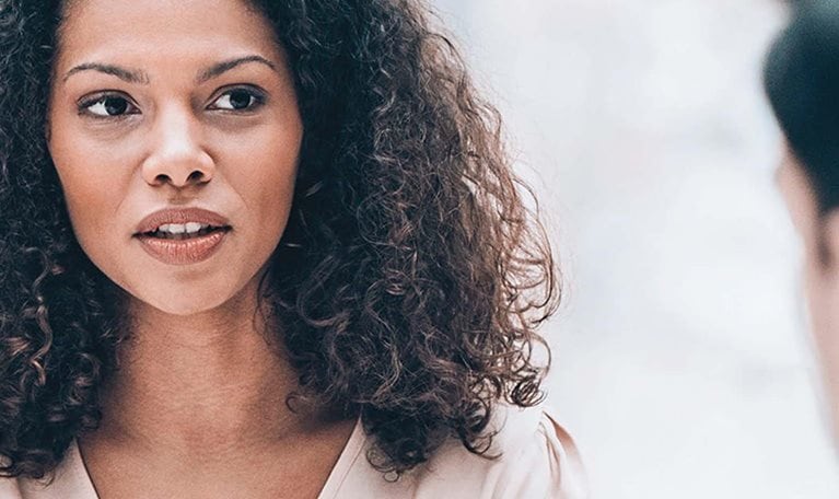 Dark-haired woman speaking with a man.