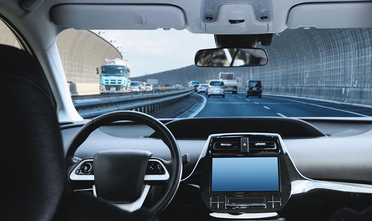 Cockpit of driverless car driving on highway viewed from rear seat. - stock photo