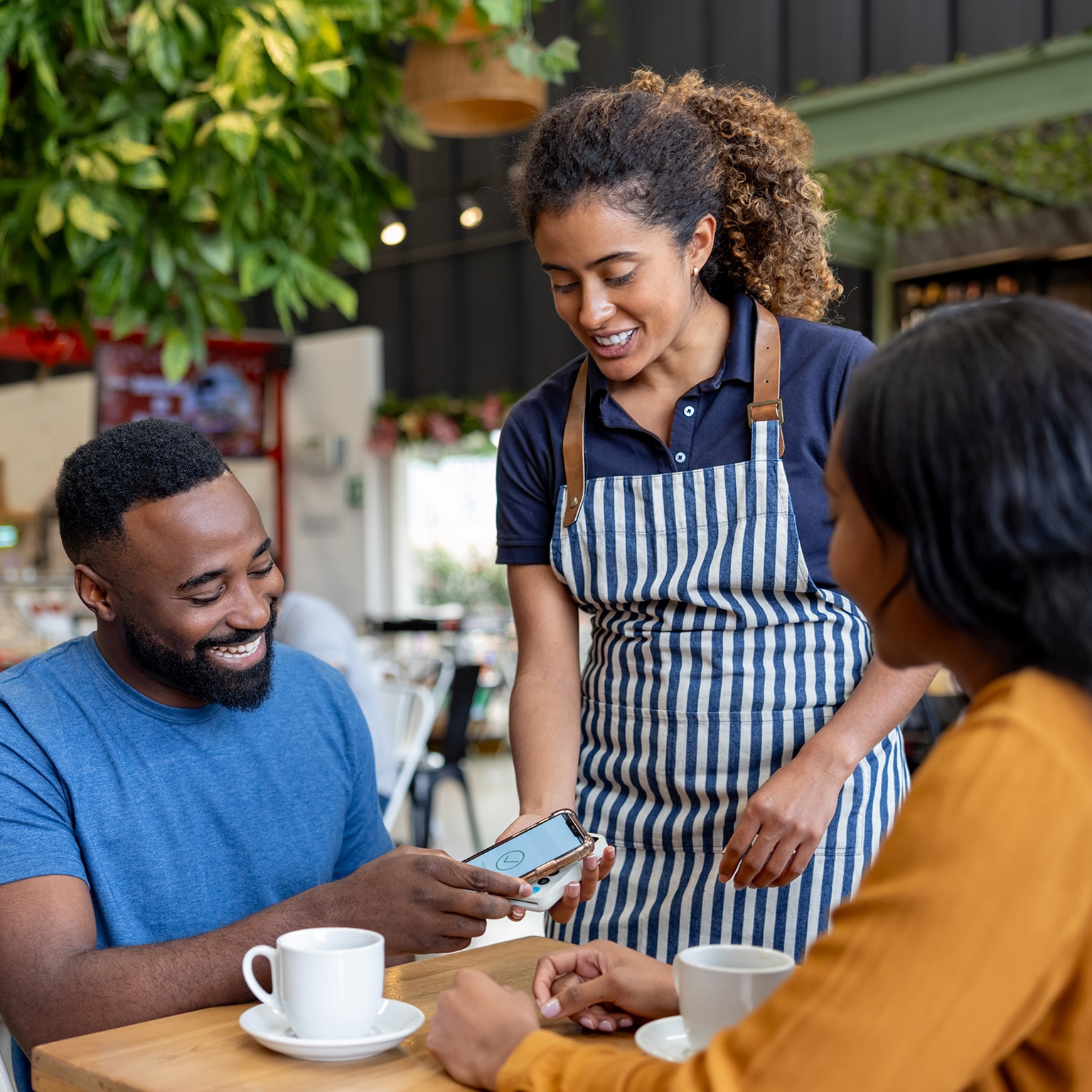 Man on a date making a mobile payment to the waitress at a coffee shop