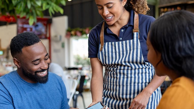 Man on a date making a mobile payment to the waitress at a coffee shop