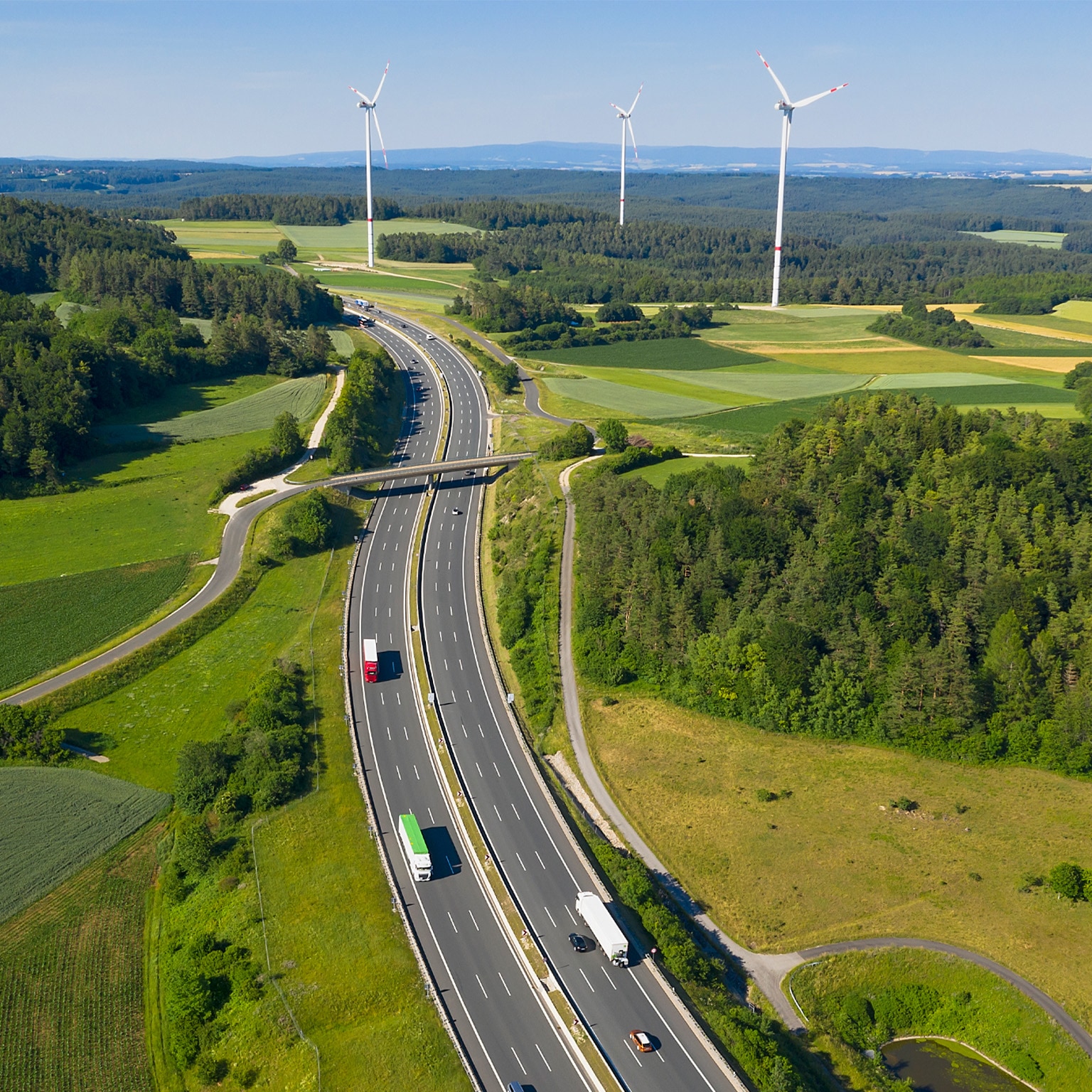 photo birdseye view of highway with wind turbines in the background