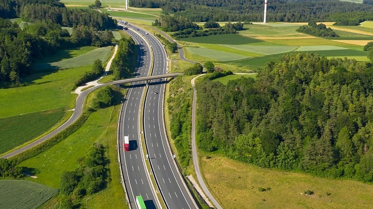 photo birdseye view of highway with wind turbines in the background