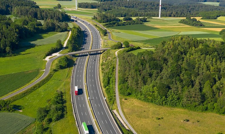 photo birdseye view of highway with wind turbines in the background