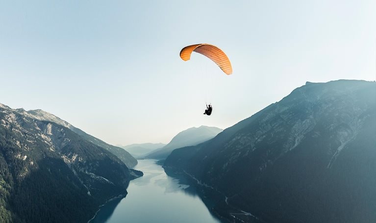 Austria, Tyrol, Paraglider over lake Achensee in the early morning - stock photo