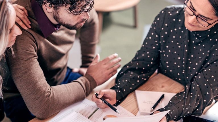 Overhead shot of couple sitting at table with female insurance agent
