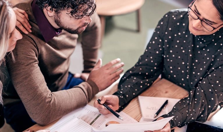 Overhead shot of couple sitting at table with female insurance agent