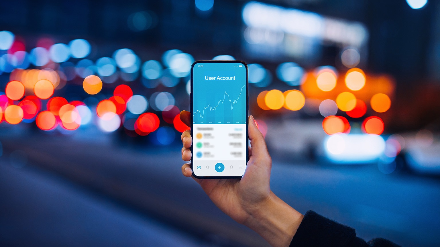 Woman's hand holding up smartphone against illuminated city street lights, using NFT investment wallet on smartphone in city, working with blockchain technologies.