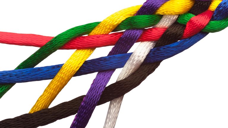 Colorful strings braided together symbolizing people joining together to form a tightly knit group or institution greater than the sum of its parts. - stock photo