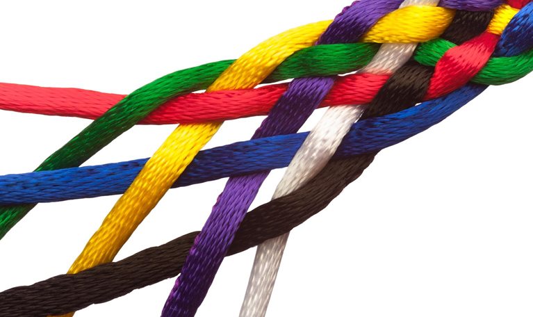Colorful strings braided together symbolizing people joining together to form a tightly knit group or institution greater than the sum of its parts. - stock photo