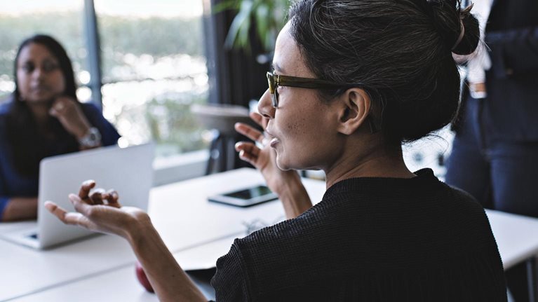 Businesswoman gesturing while in discussion with colleagues