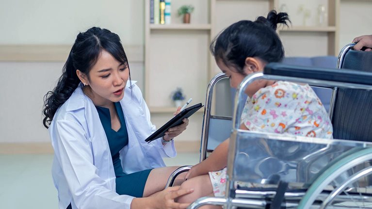 Asian chinese female doctor having discussion with her handicapped amputee leg patient at reception counter of hospital