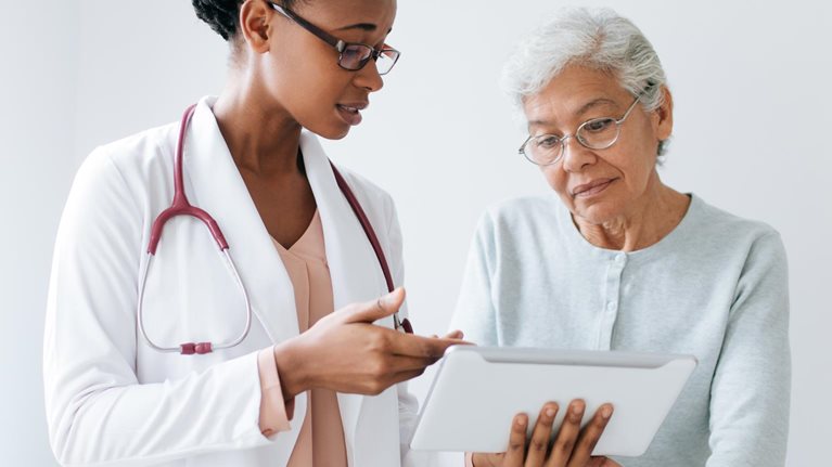 doctor showing woman results on tablet - stock photo