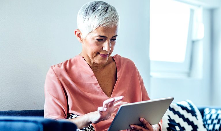 Older Caucasian woman using digital tablet on sofa