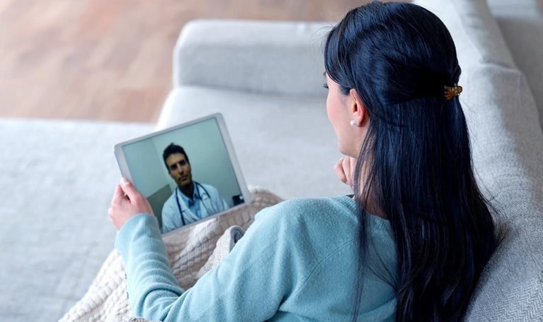 Woman at home feeling poorly and talking to her doctor on a video call