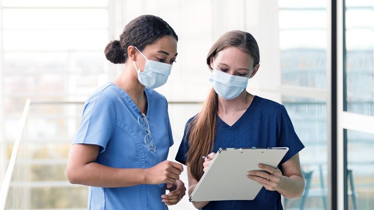 Two female surgeons confer before seeing patients in the hospital