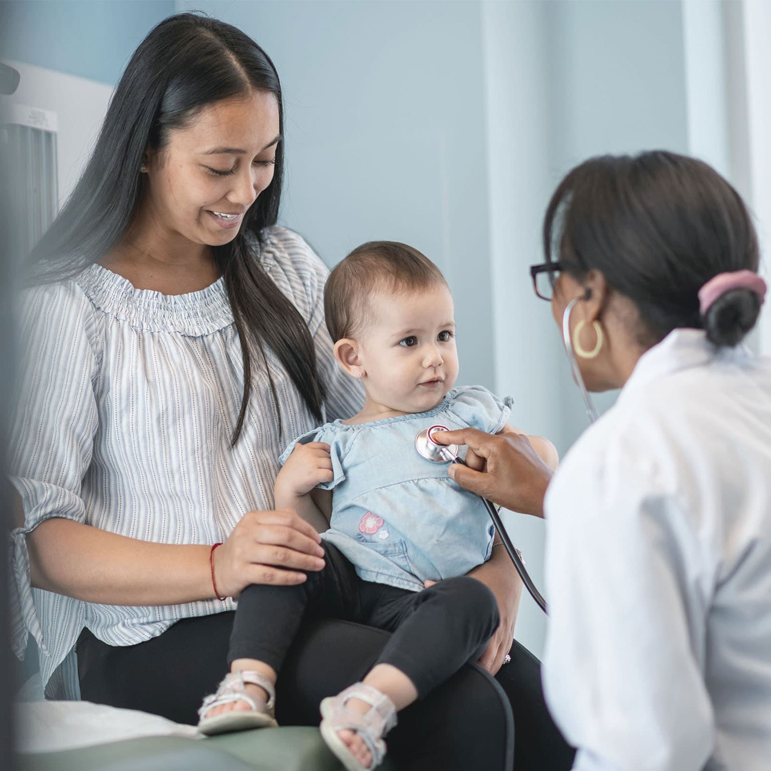 Female pediatrician checks heart of baby girl