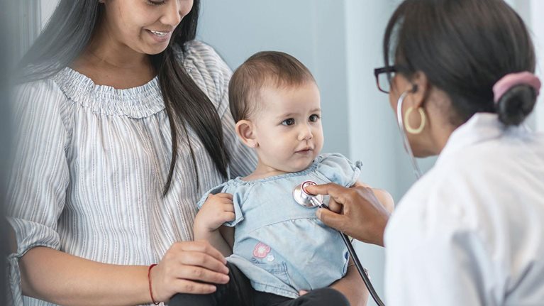 Female pediatrician checks heart of baby girl