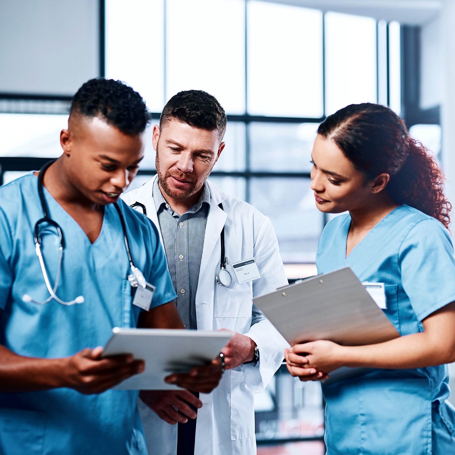 A group of medical practitioners using a digital tablet together in a hospital