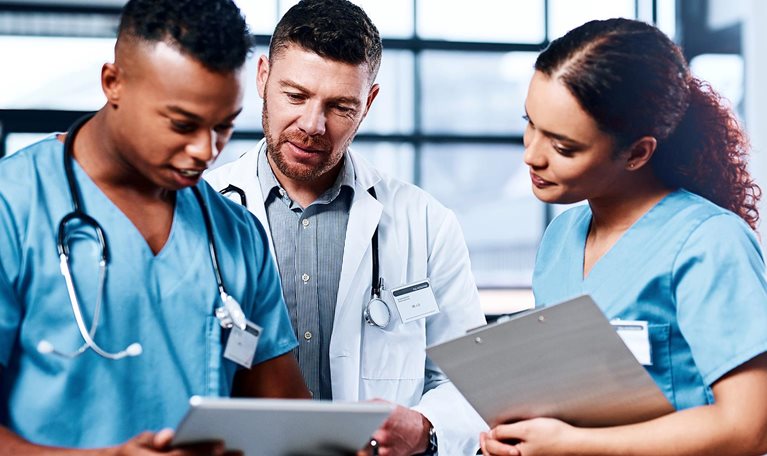 A group of medical practitioners using a digital tablet together in a hospital