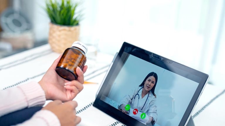 A young woman engaged in a video conference with her doctor.