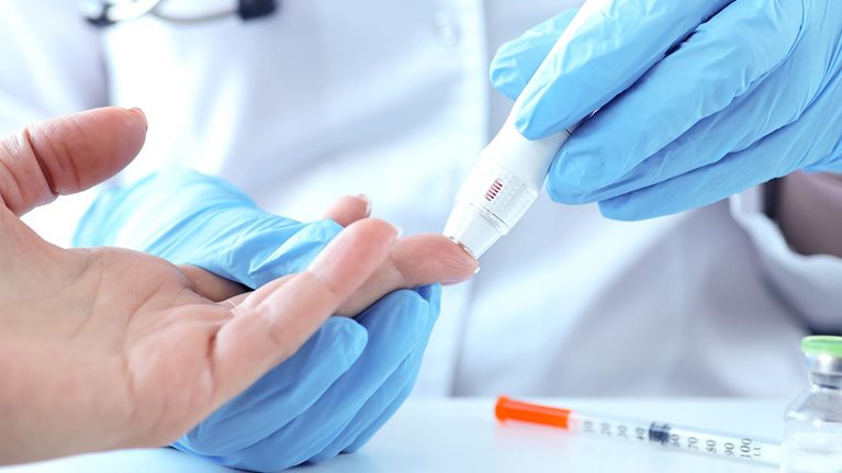 Doctor with gloves piercing patients finger with lancet closeup - stock photo