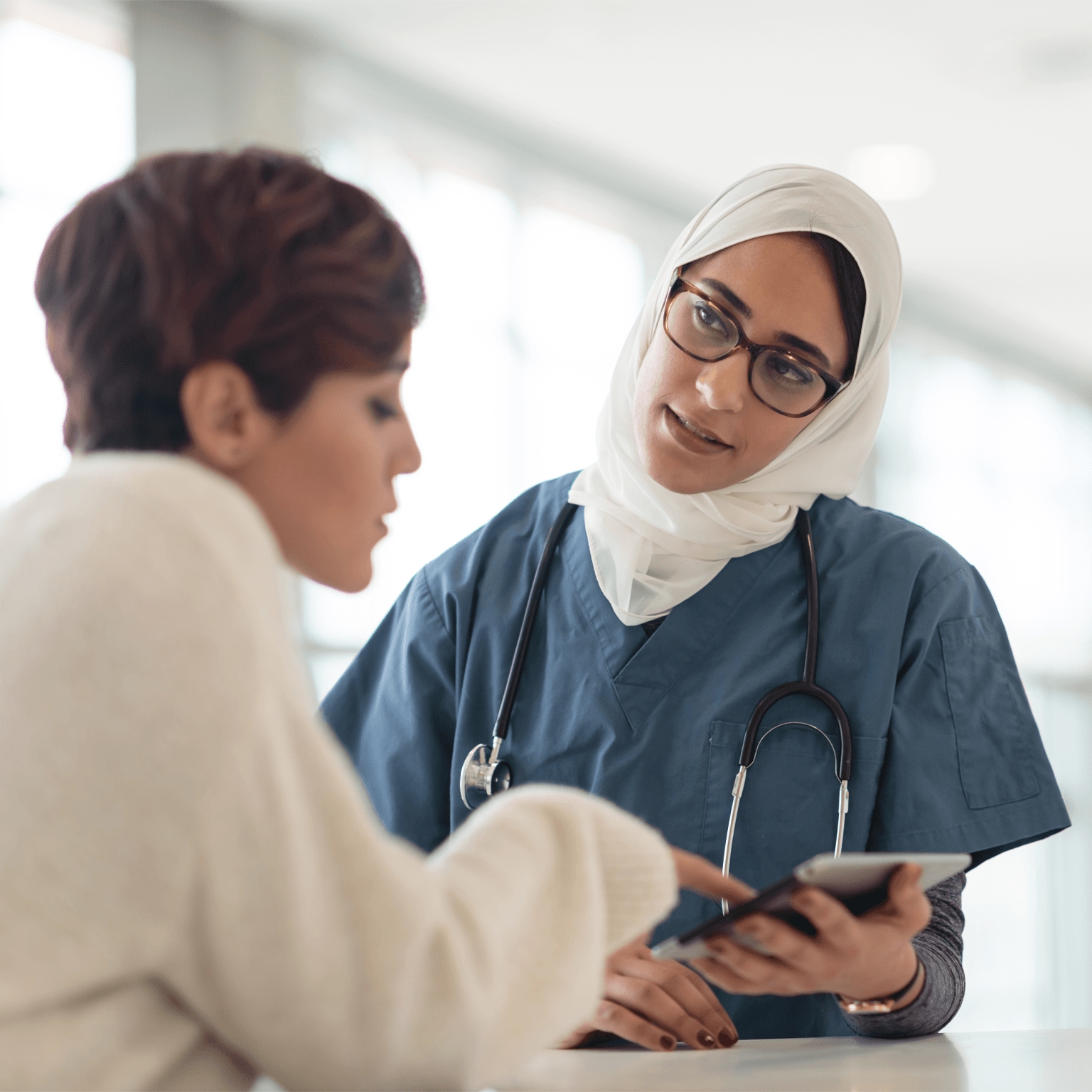 Saudi Arabian nurse with tablet helping patient