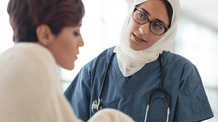 Saudi Arabian nurse with tablet helping patient