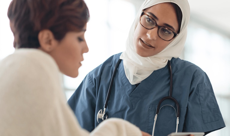 Saudi Arabian nurse with tablet helping patient