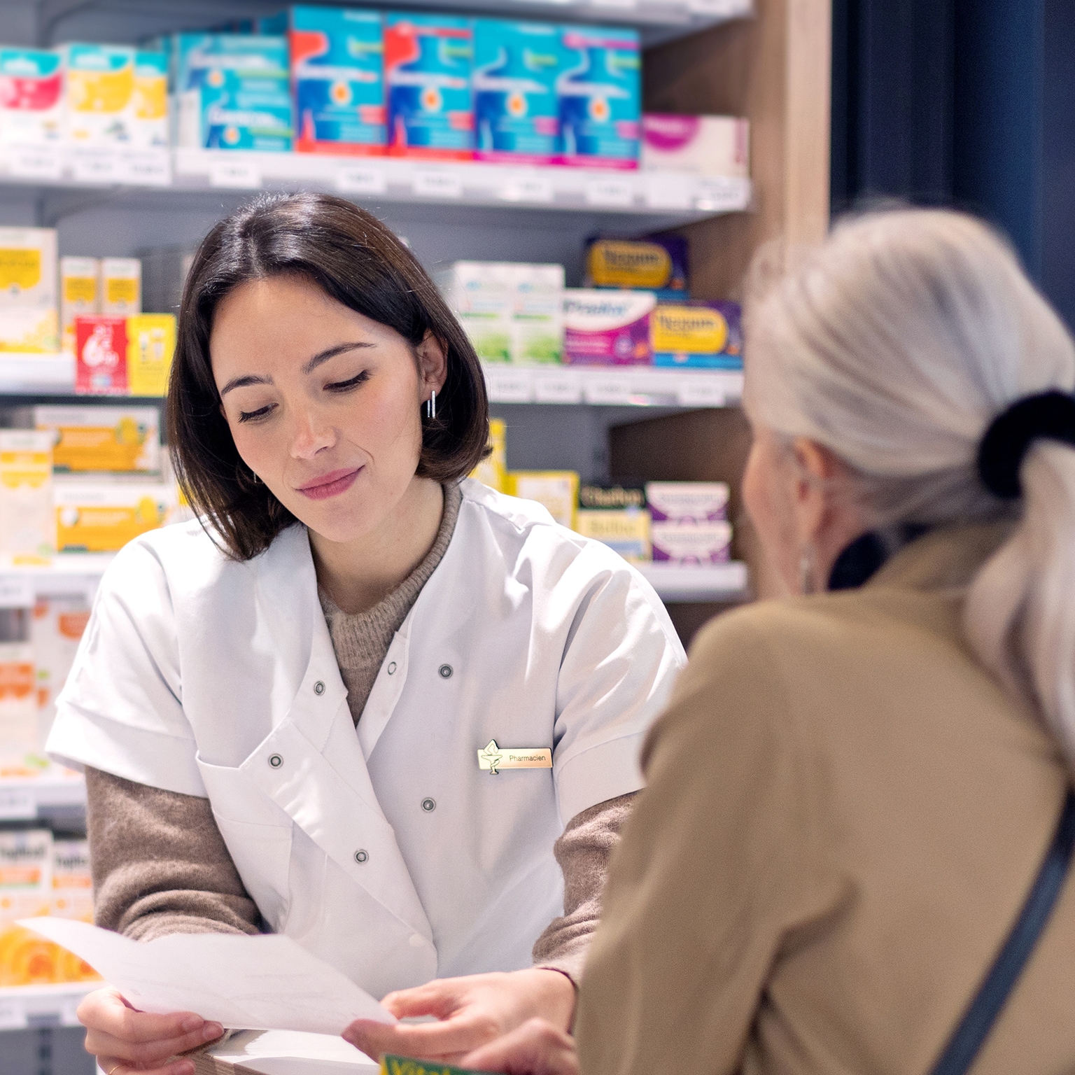 A female pharmacist discussing a prescription with an elderly lady customer at the service counter in a pharmacy