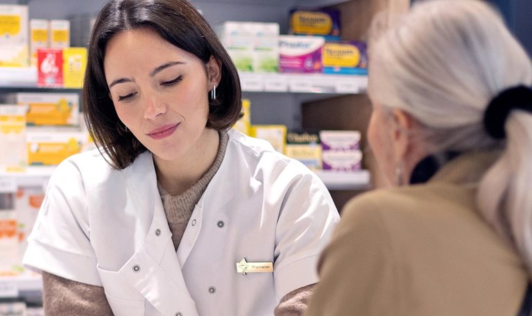 A female pharmacist discussing a prescription with an elderly lady customer at the service counter in a pharmacy