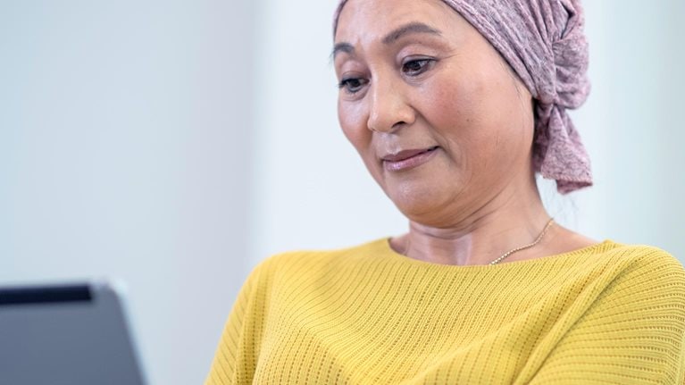 Woman in yellow reading on a tab