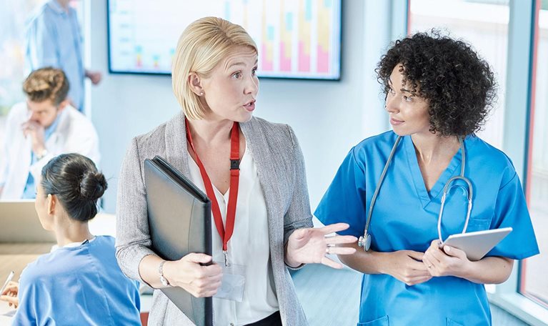 A businesswoman meets with a doctor prior to sitting at a boardroom meeting in a hospital