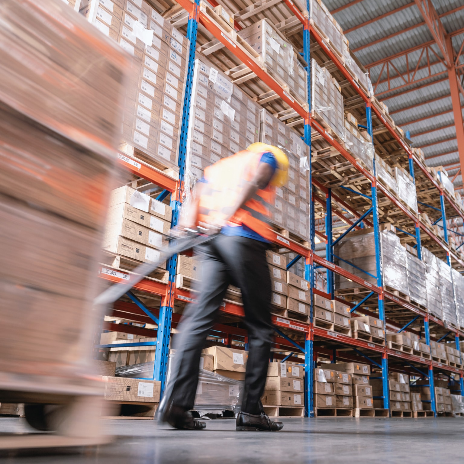 Motion blurred of warehouse worker moving boxes on pallet in warehouse