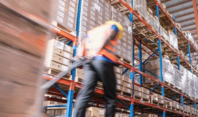 Motion blurred of warehouse worker moving boxes on pallet in warehouse