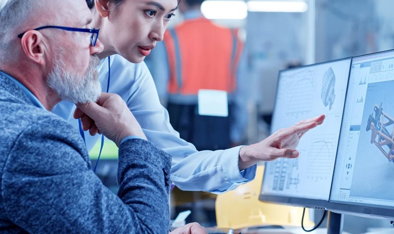 Asian female technician discusses work with middle aged designer.