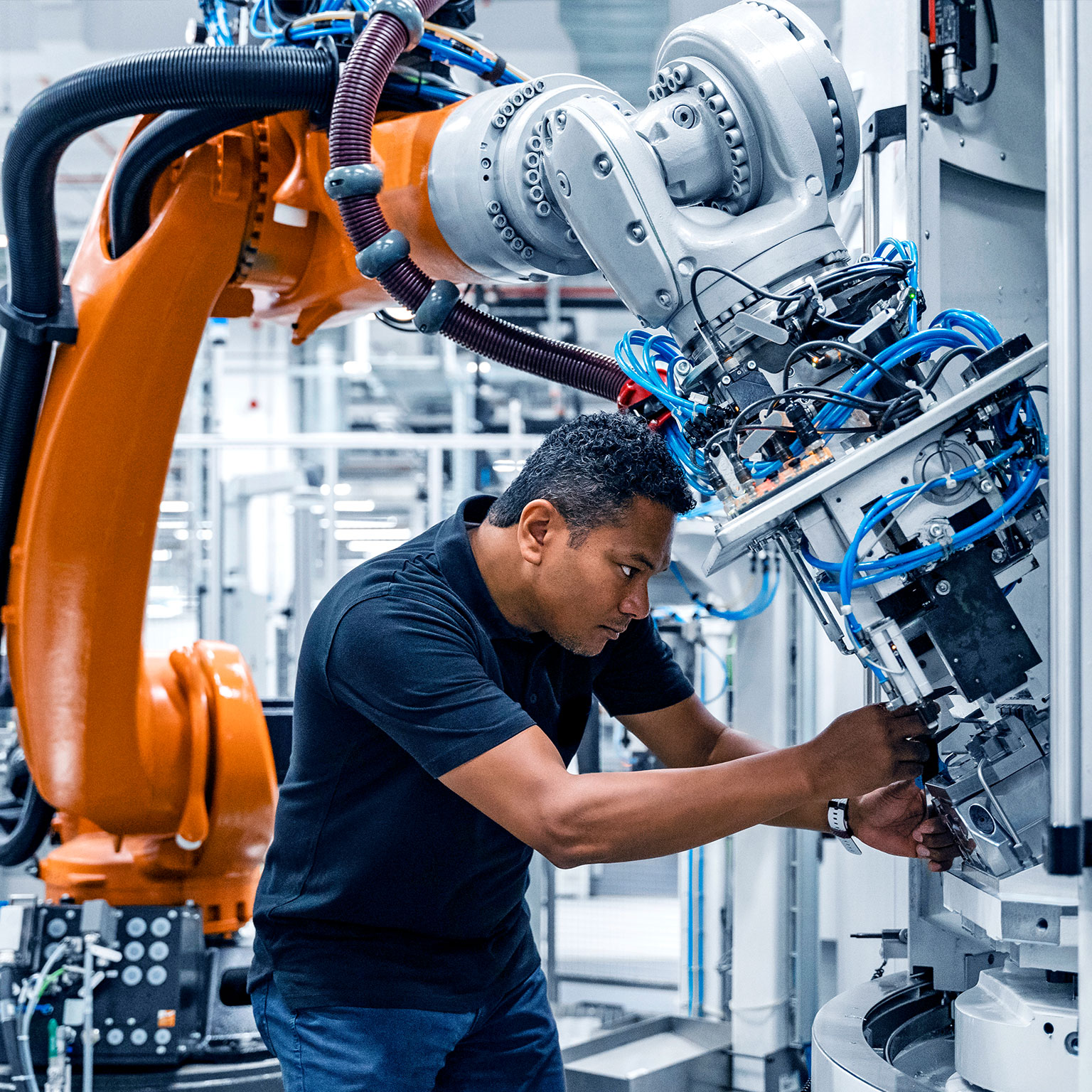 Engineer examining robotic arm in factory