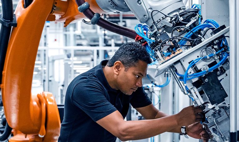 Engineer examining robotic arm in factory