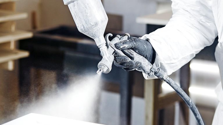 Close-up of industrial worker using paint gun for applying paint