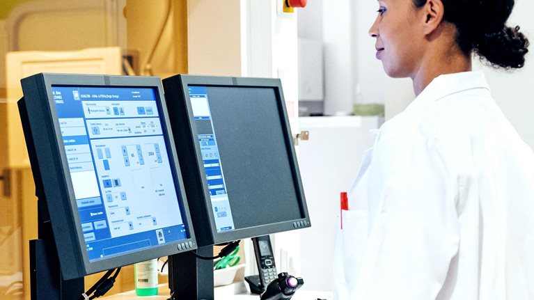 Woman in white overcoat working on desktops