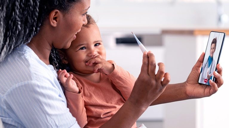 Woman and baby daughter using a smartphone to communicate with the doctor.