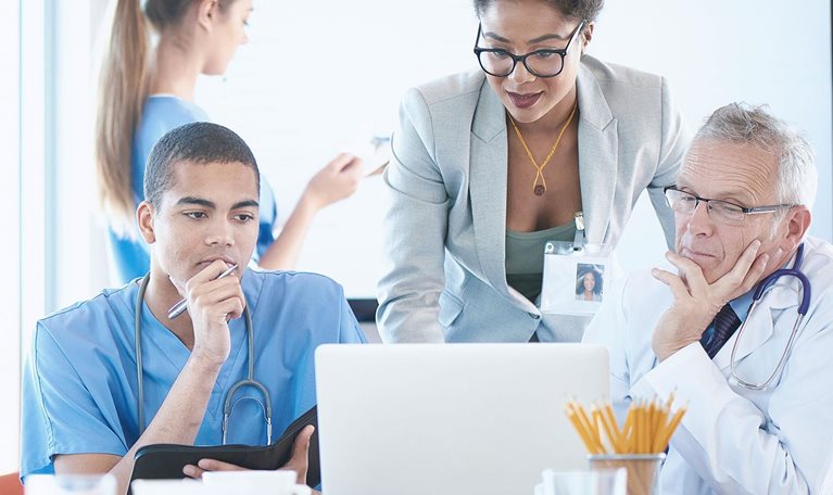 A medical team are discussing something around a boardroom table.