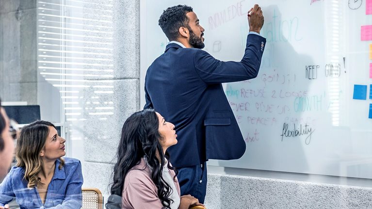 Coworkers writing on whiteboard