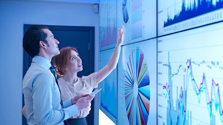 Business colleagues studying graphs on screen in meeting room