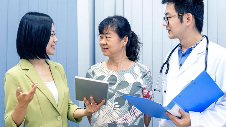 Asian care manager assisting her customer in communicating with doctor