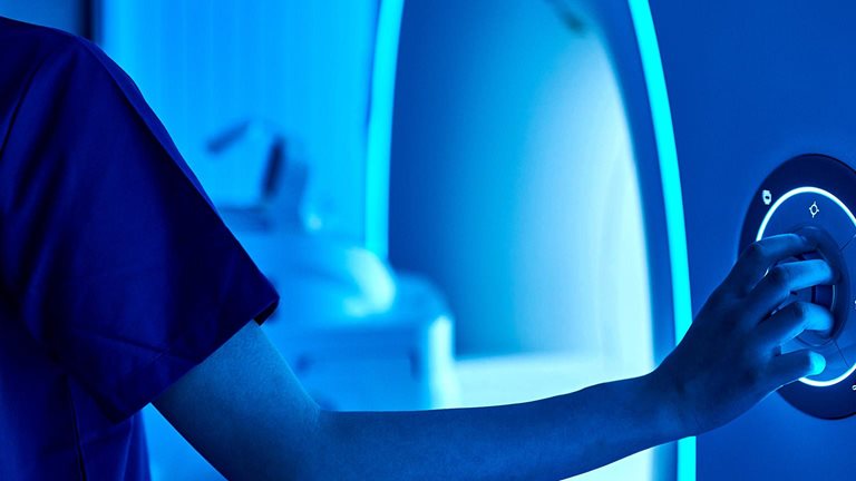 A healthcare professional adjusts the controls of a medical imaging machine.