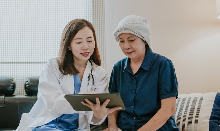 Young female doctor use tablet to explain her senior patient about cancer and medication for next step