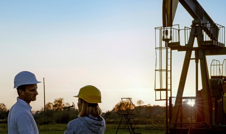 Two engineers standing near a pumpjack