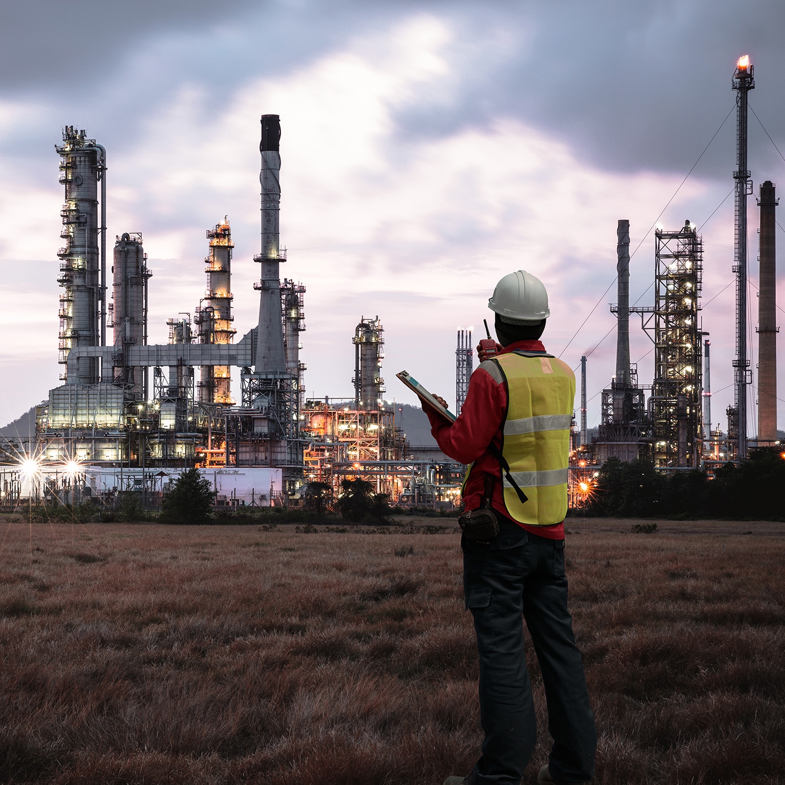 The image shows an engineer or safety professional at a petrochemical or industrial plant.